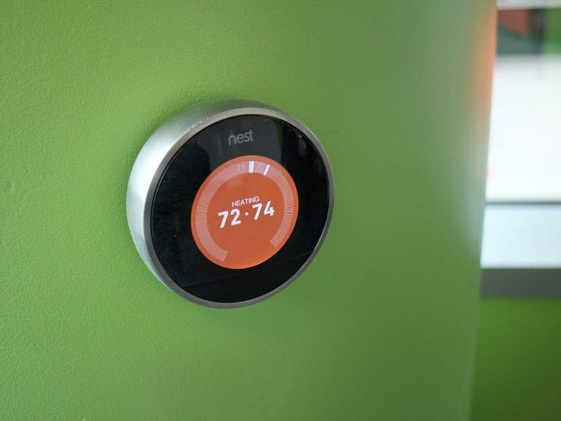 a nest thermostat on a green wall