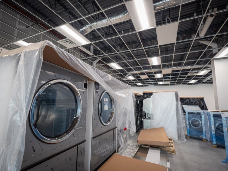 New washing machines are covered in tarps and plastic as they await installation.