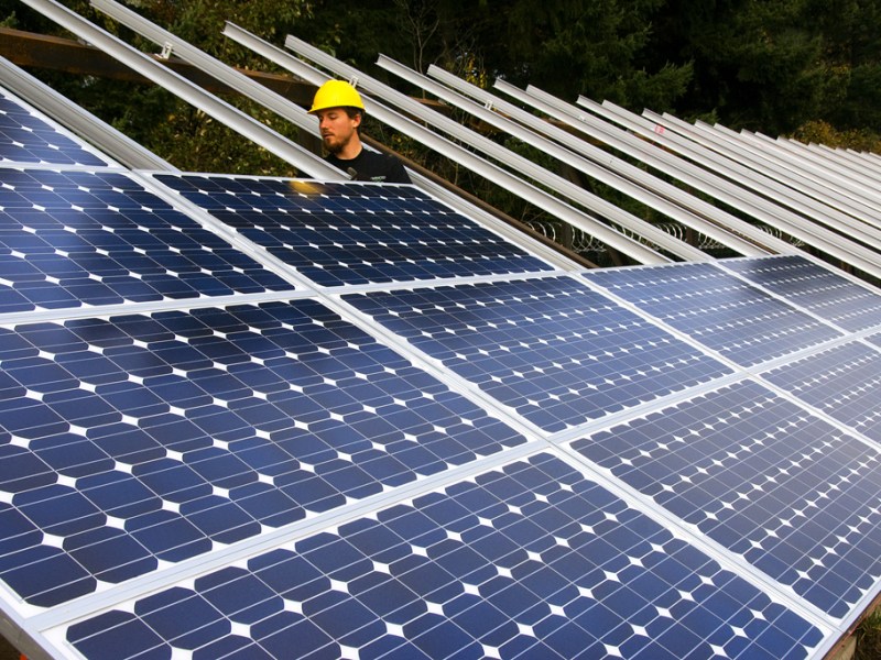 A person in a hard hat assembles solar panels.