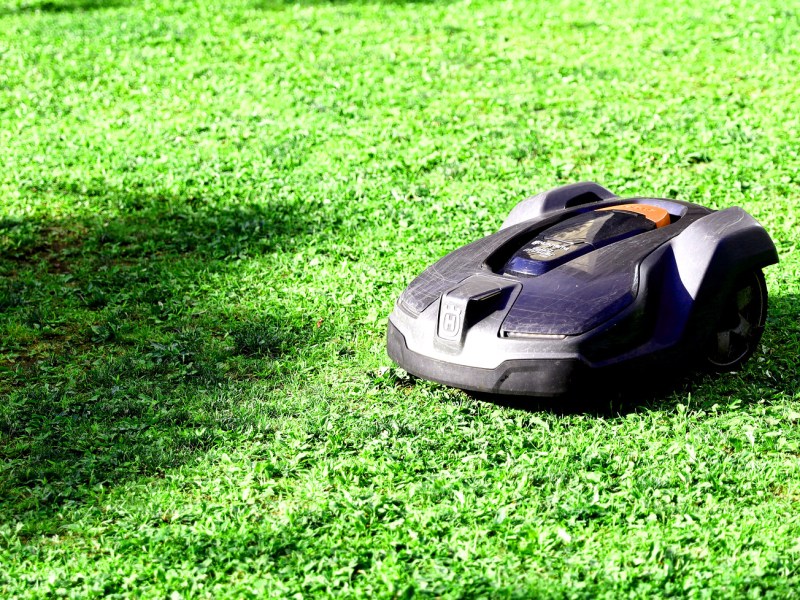 A robotic electric lawnmower sits on a green lawn