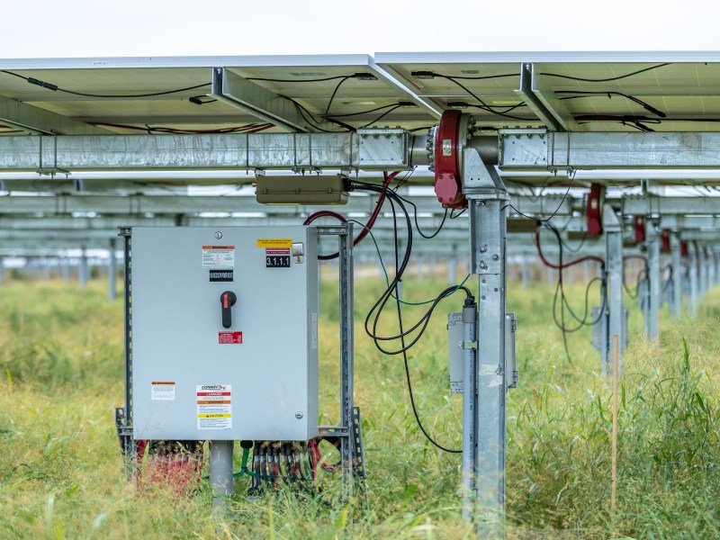 An electrical box beneath solar panels in a field in Minnesota.