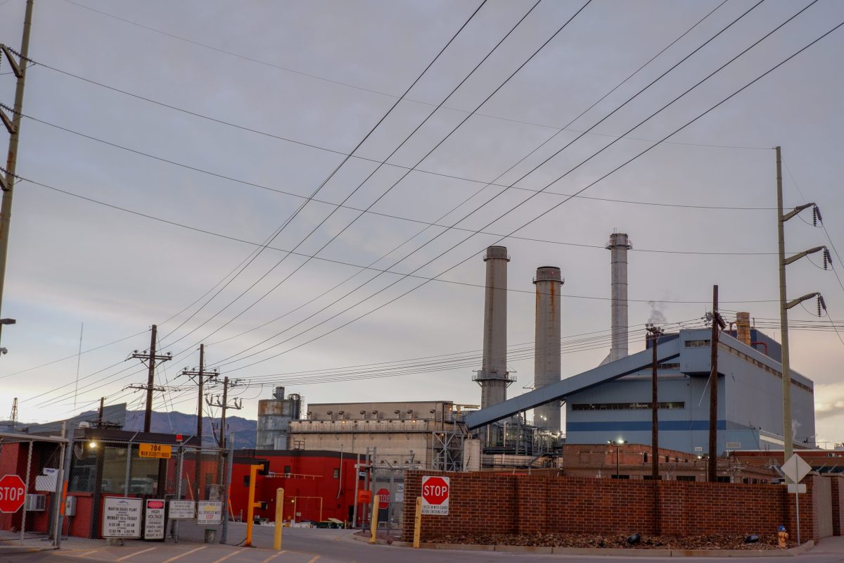 A power plant with three smokestacks and power lines running to it.