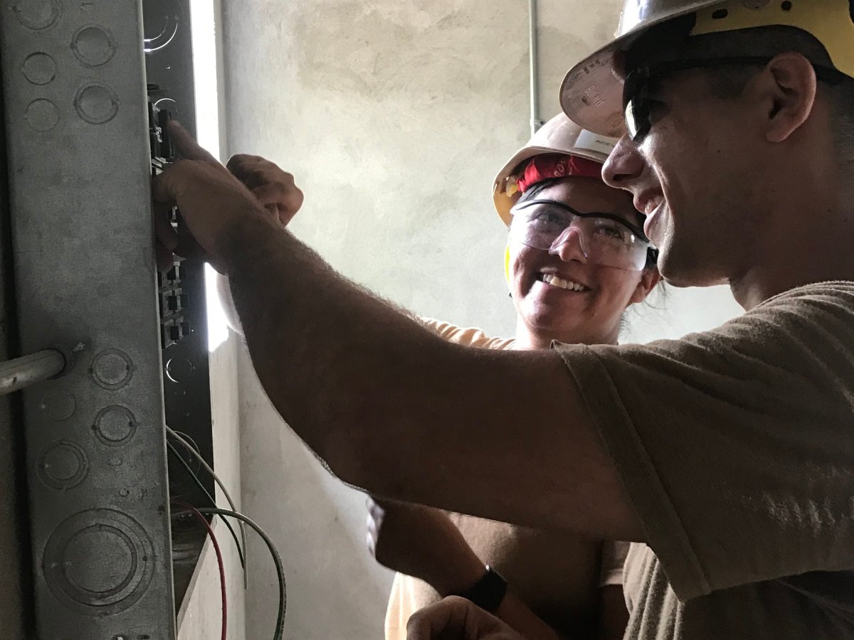 Electricians work on a breaker panel