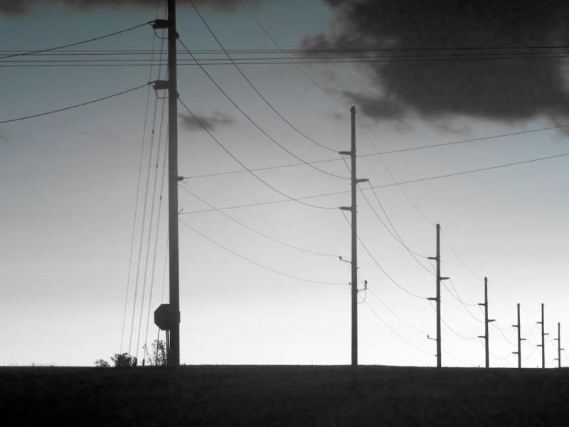 A long line of silhouetted electric posts disappearing into the distance.