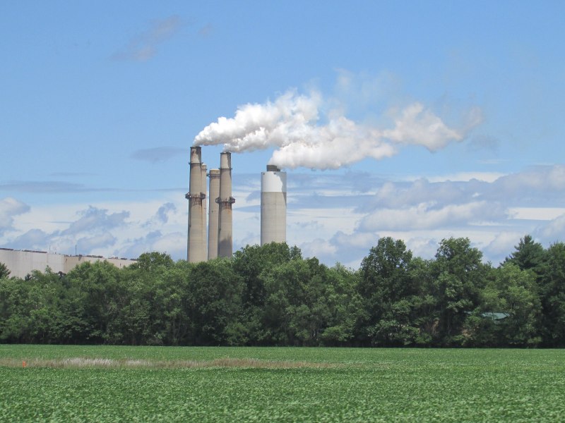 Smokestacks at the R.M. Schahfer Generating Station appear behind a line of trees and a field