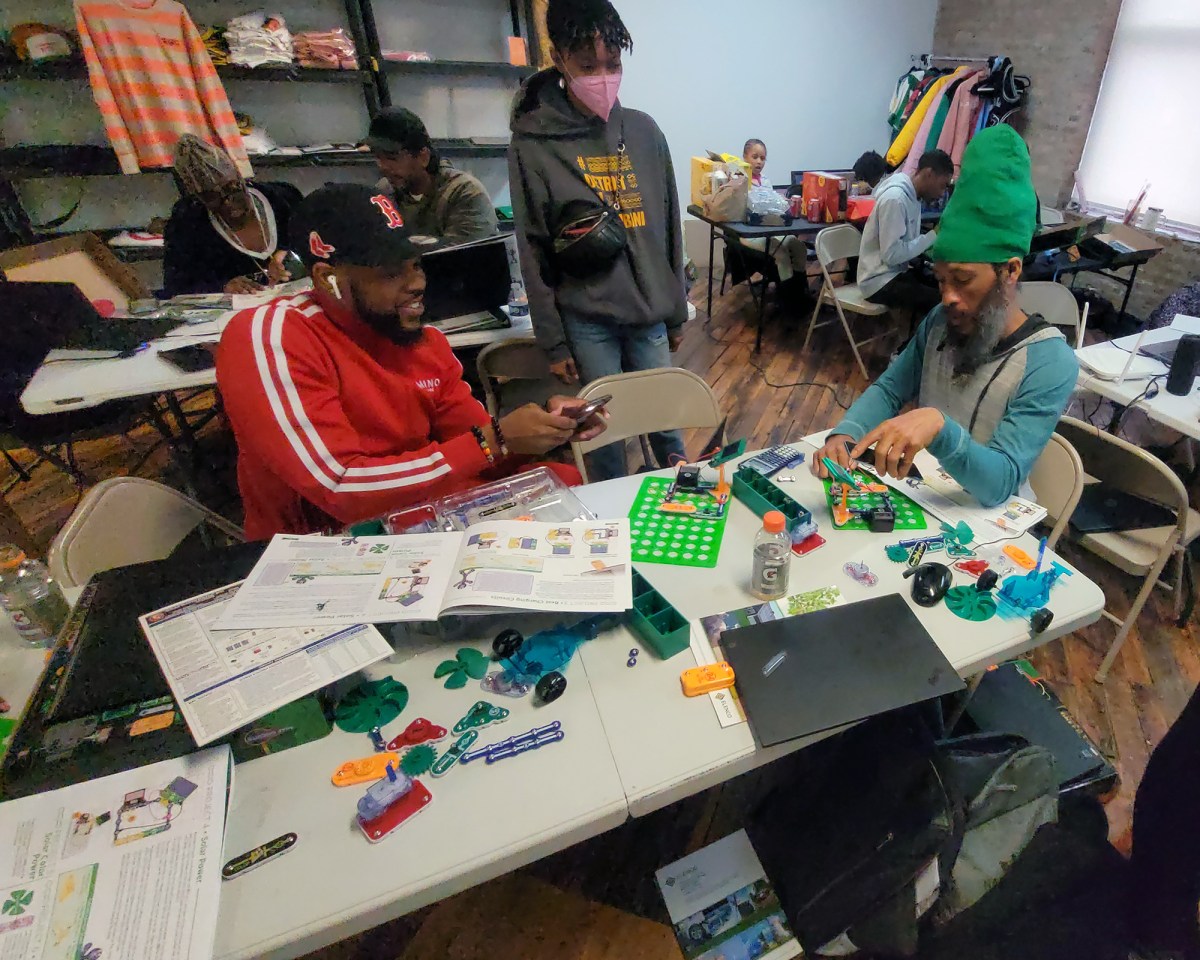 A group of trainees arrange components of a model solar installation.