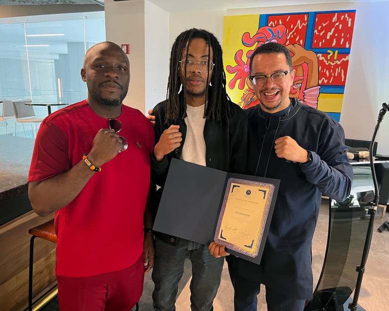 From left, Senyo Ador, Eliyah Payton, and Osei Andrews-Hutchinson, holding a certificate of completion, pose for a photo.