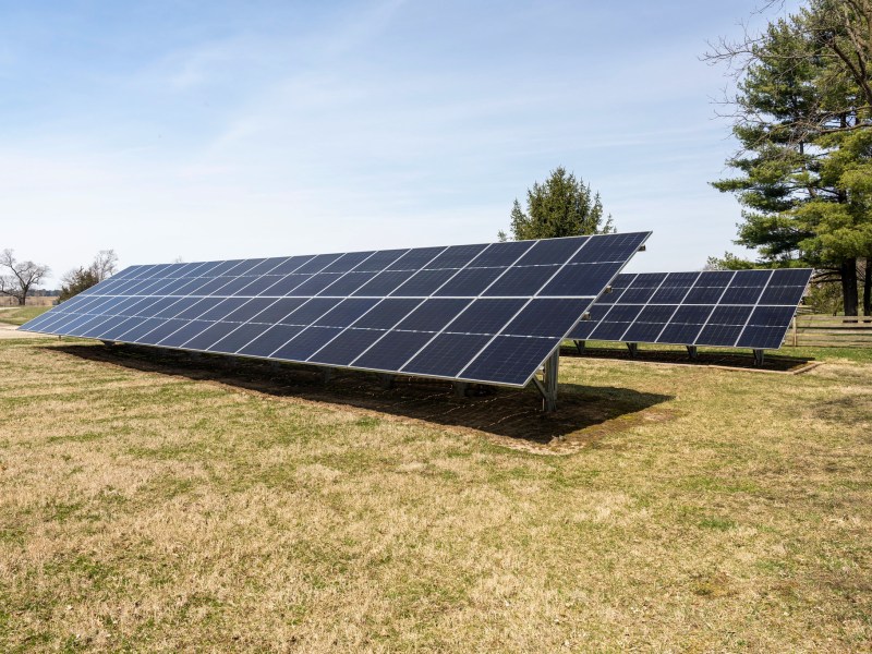 Solar panels in a grassy area near a farm