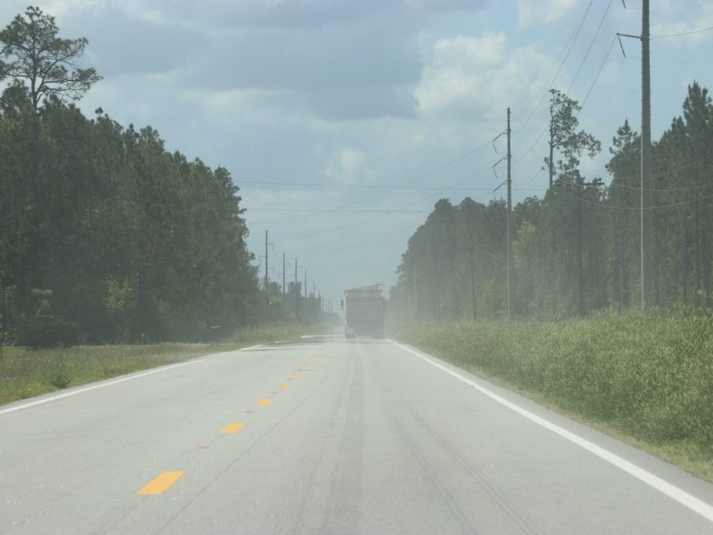 A commercial truck carrying waste to Chesser Island Road Landfill kicks up dust as it barrels down the highway.