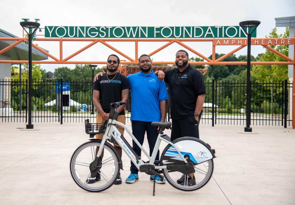 Kent Wallace, Paris Wallace, and Ronnell Elkins pose with a YoGo electric bike in Youngstown.